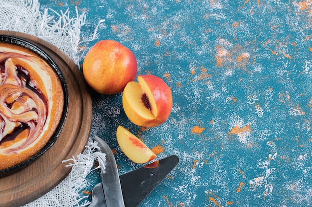 Pastel de fresa con melocotones amarillos alrededor.