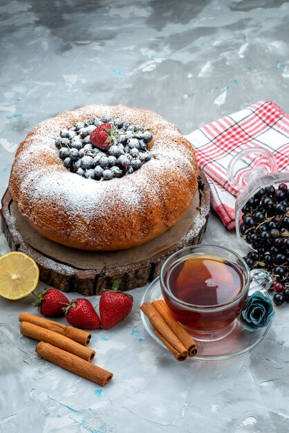 Un pastel de frutas de vista frontal delicioso y redondo formado con azul fresco, bayas y té en azúcar dulce, galleta de pastel brillante