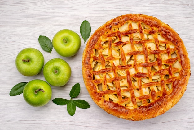 Foto gratuita un pastel de frutas de vista superior redondo delicioso con manzanas en la mesa de luz pastel galleta fruta