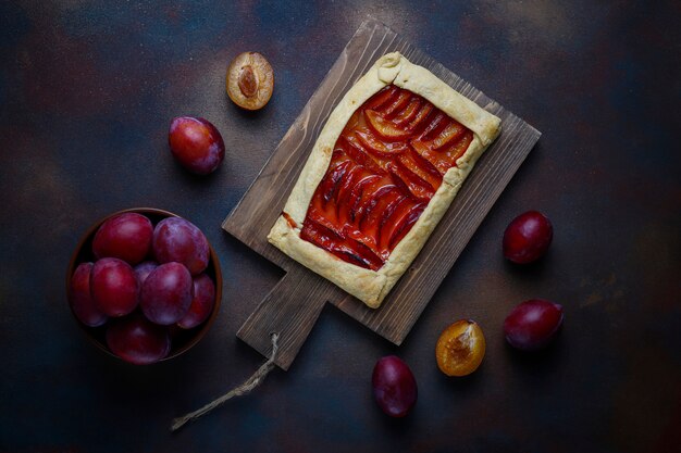 Pastel de galette de ciruelas frescas con ciruelas crudas en la oscuridad