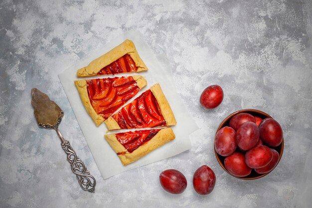 Pastel de galette de ciruelas frescas con ciruelas crudas en la oscuridad