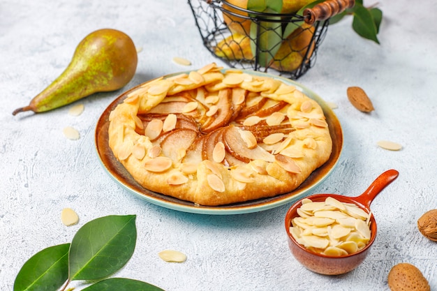 Pastel de galette de pera casero con hojas de almendras y peras verdes maduras frescas