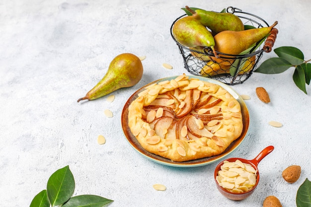 Pastel de galette de pera casero con hojas de almendras y peras verdes maduras frescas