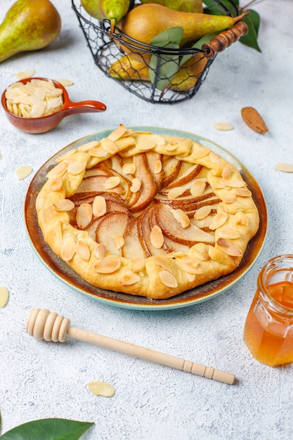 Pastel de galette de pera casero con hojas de almendras y peras verdes maduras frescas