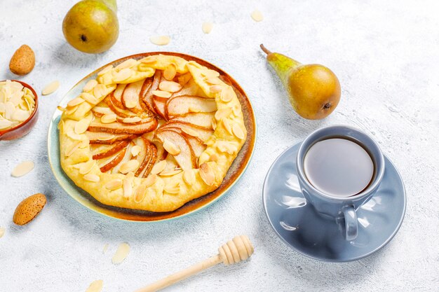 Pastel de galette de pera casero con hojas de almendras y peras verdes maduras frescas