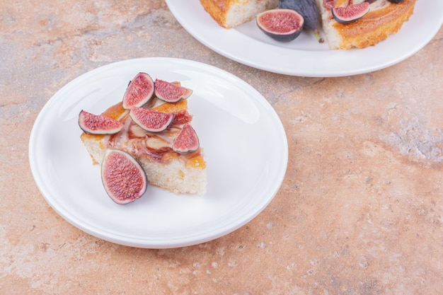 Un pastel con higos en un plato blanco sobre el mármol.