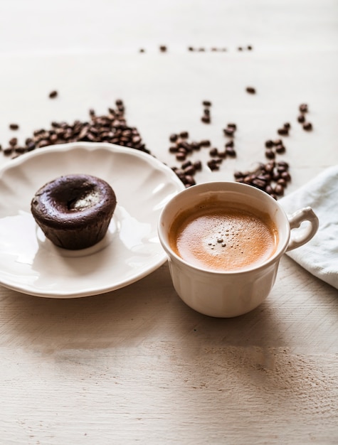 Foto gratuita pastel de lava de choco en un plato con taza de café y granos de café tostados