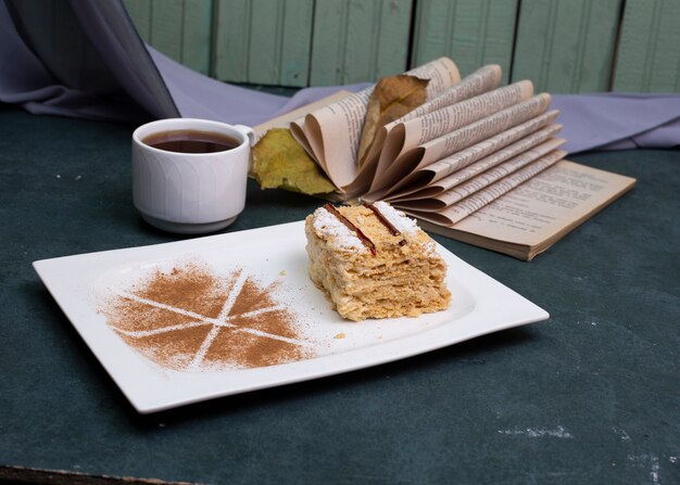 Pastel Medovik con cacao en polvo y una taza de té.