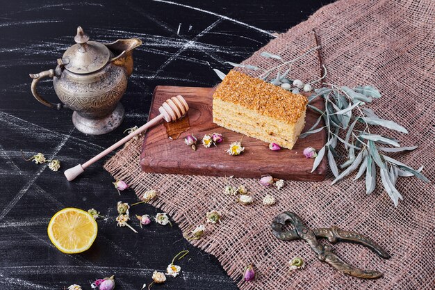 Pastel de miel sobre tabla de madera con flores secas y tetera.