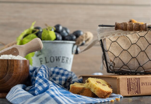 Pastel con pasas, harina y uvas en mesa de mármol con libro