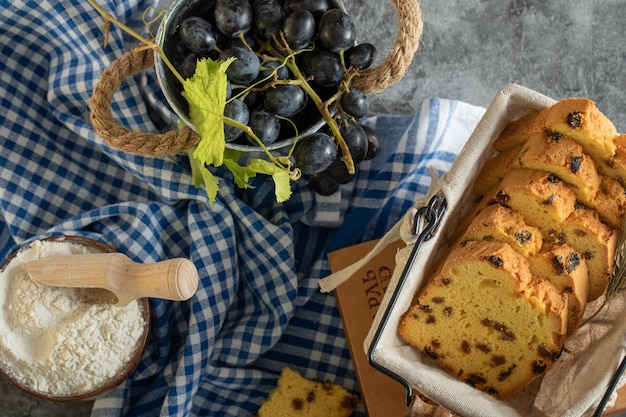 Pastel de pasas, tazón de harina y uvas en la superficie de mármol