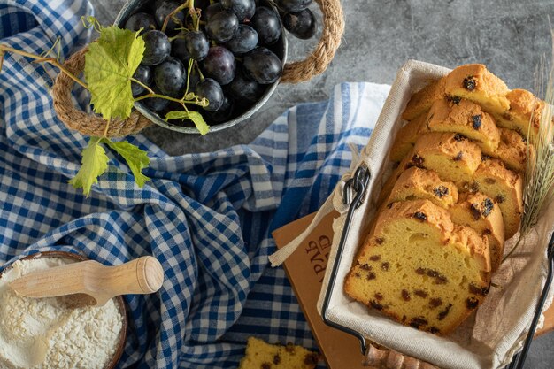 Pastel de pasas, tazón de harina y uvas en la superficie de mármol