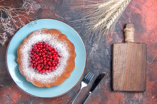 un pastel un pastel con grosellas rojas la tabla de cortar de madera cuchillo y tenedor