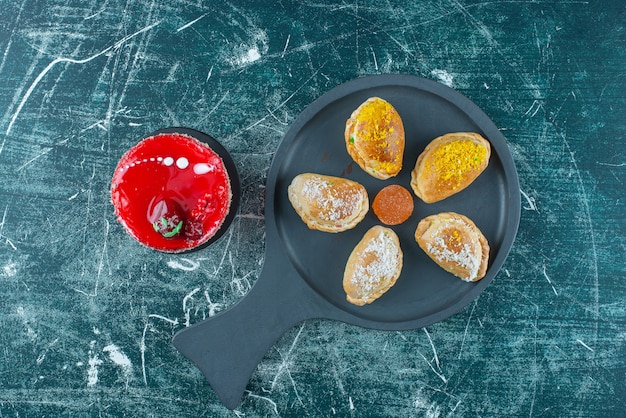 Pastel pequeño junto a un manojo de bollos en una bandeja para servir en azul.