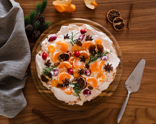 Pastel plano de merengue decorado con rodajas de naranja y rosa mosqueta