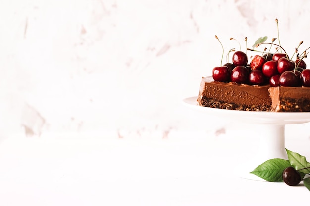 Pastel de queso de chocolate sin hornear decorado con cerezas frescas y espacio de copia de menta para su texto