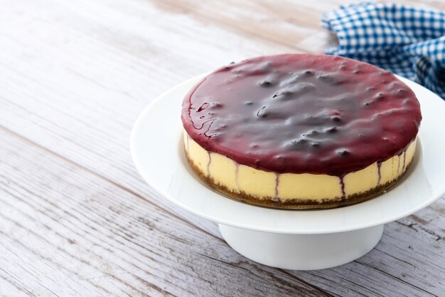 Pastel de queso dulce con bayas azules sobre mesa de madera