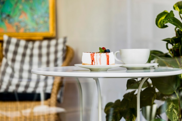 Pastel de queso sabroso dulce con las bayas y la taza de café en la taza blanca en la cafetería