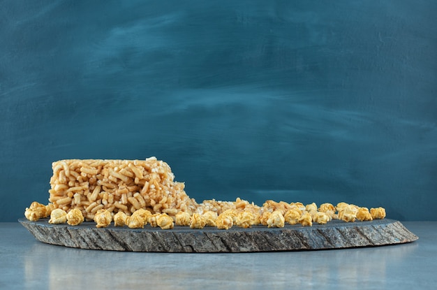 Pastel recubierto de caramelo y un montón de palomitas de maíz en una placa sobre la superficie de mármol