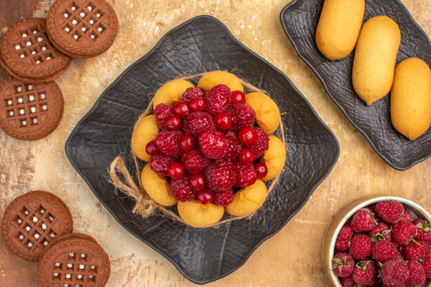 Foto gratuita un pastel de regalo y galletas en placas marrones frutas en tabla de colores mezclados