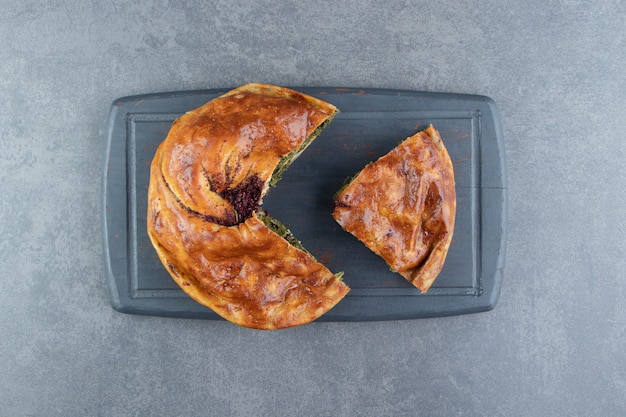 Pastel relleno de verduras sobre tabla de cortar negra.