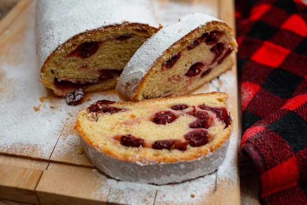 Pastel de rollo con relleno de cereza cubierto con azúcar en polvo sobre una tabla para cortar