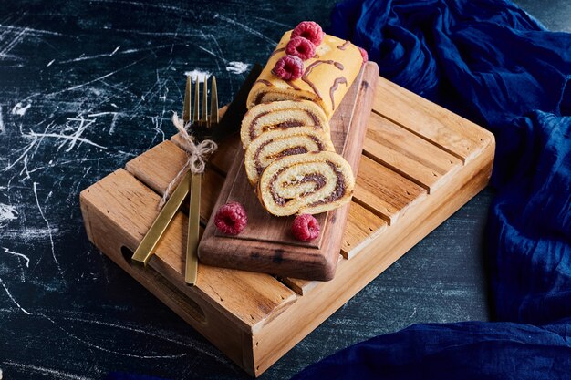 Pastel de rollo en rodajas con relleno de chocolate en una bandeja de madera.