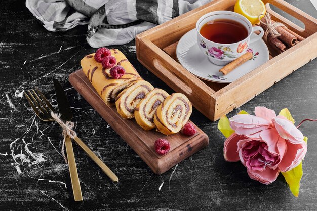Pastel de rollo en rodajas con relleno de chocolate servido con una taza de té.