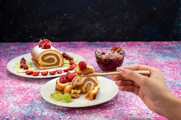 Pastel de rollo de vista frontal con frutas dentro de la placa blanca.