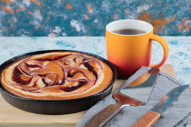 Pastel en una sartén negra con melocotón y una taza de té.