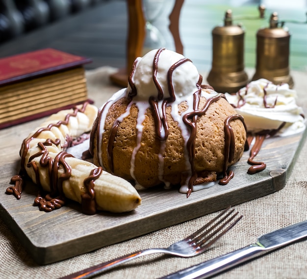 Pastel sobre tabla de madera con crema de plátano vista lateral de chocolate