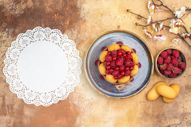 Pastel suave recién horneado con frutas, galletas y una servilleta en la tabla de colores mezclados