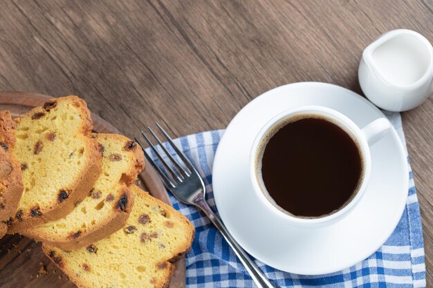 Pastel de sultana en rodajas servido con una taza de café.