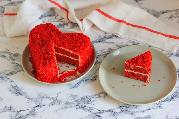 Pastel de terciopelo rojo en forma de corazón sobre la mesa de mármol.