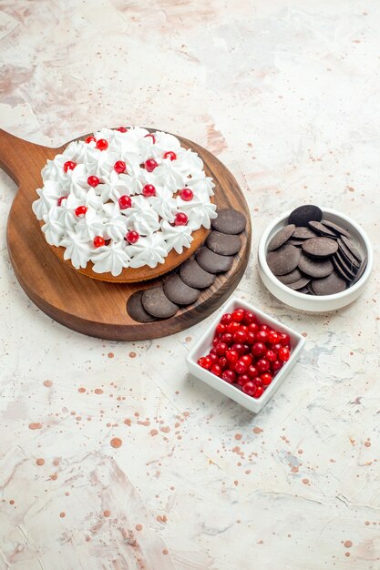 Pastel de vista inferior con crema pastelera blanca y chocolate en tazones de tabla de cortar con bayas y chocolate en superficie gris claro