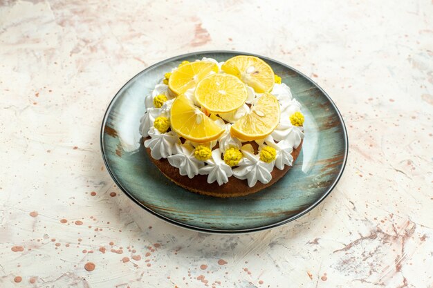 Foto gratuita pastel de vista inferior con crema pastelera blanca y rodajas de limón en un plato redondo sobre una mesa gris claro