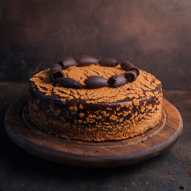 Pastel con vista lateral de chocolate sobre piedra sucia y tabla de cortar