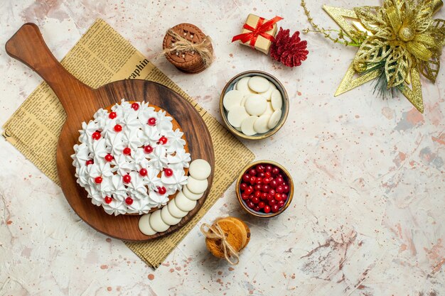 Pastel de vista superior con crema pastelera blanca sobre tablero de madera en periódico y adornos navideños