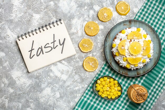 Pastel de vista superior con crema pastelera y limón en bandeja de galletas atadas con caramelos de cuerda en un tazón sobre mantel a cuadros blanco verde limón