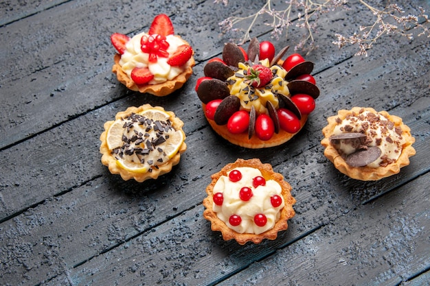 Pastel de vista superior con frambuesa de fruta de cornel y chocolate rodeado de tartas en superficie oscura