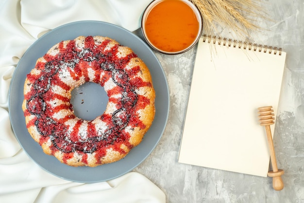 Pastel de vista superior con fresa en un plato redondo miel en un tazón bloc de notas de palo de miel en la mesa