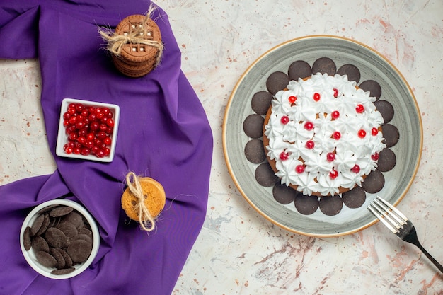 Pastel de vista superior en galletas de horquilla de placa atadas con cuencos de cuerda con bayas y chocolate en mantón púrpura