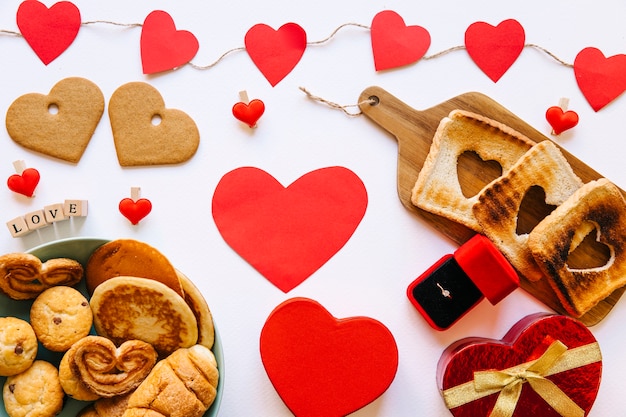 Foto gratuita pastelería cerca de anillo de compromiso y corazones