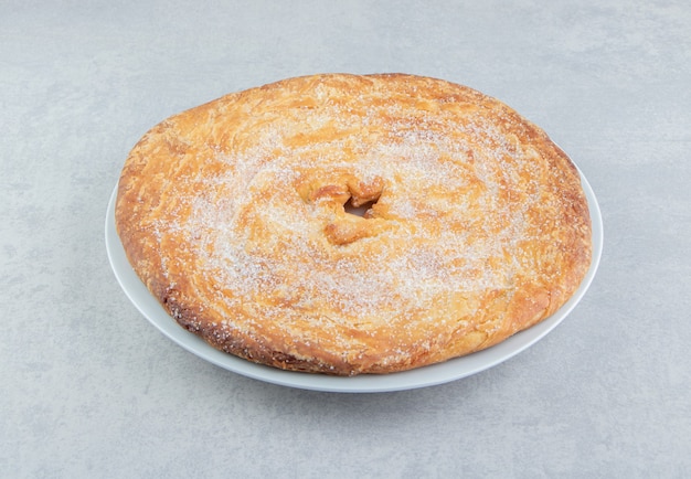 Pastelería circular decorada con polvo en plato blanco.