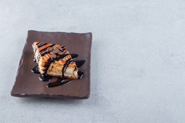 Pastelería dulce decorada con chocolate colocada en un plato oscuro. Foto de alta calidad