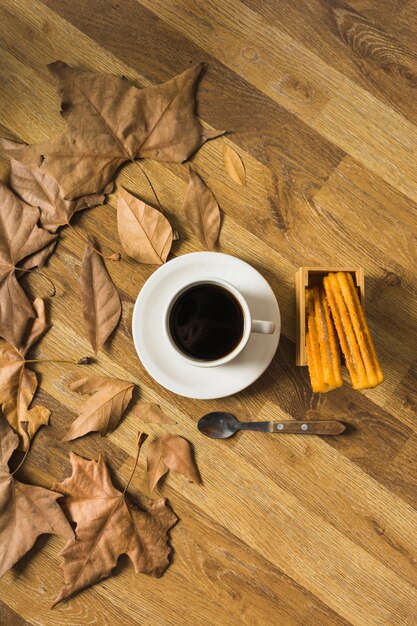 Pastelería fresca y café cerca de las hojas en el piso