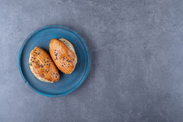 Pastelería con queso sobre placa de madera, sobre el mármol.