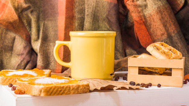 Pastelería y taza cerca de cortinas