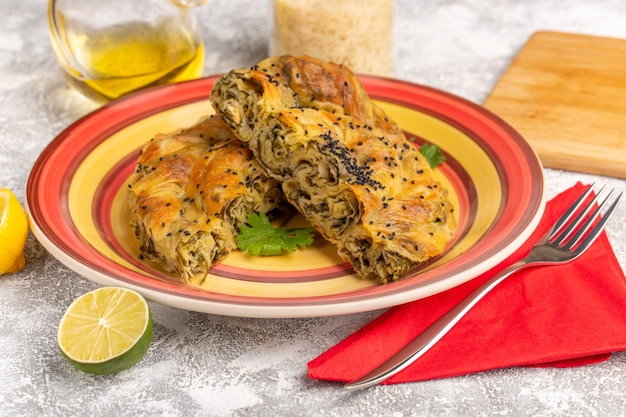 Pastelería de vista frontal con comida de masa deliciosa carne dentro de la placa con aceite de limón en el escritorio de luz blanca.