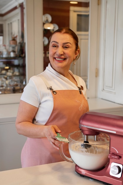 Foto gratuita pastelero femenino con batidora en una pastelería
